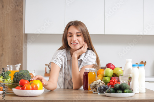 Young woman with healthy food on table in kitchen. Diet concept
