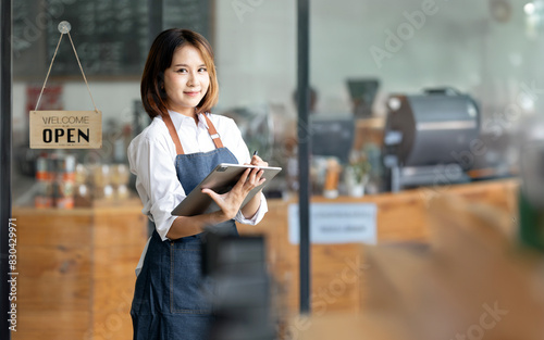 Cute waitress or cafe business owner entrepreneur with tablet looking at camera