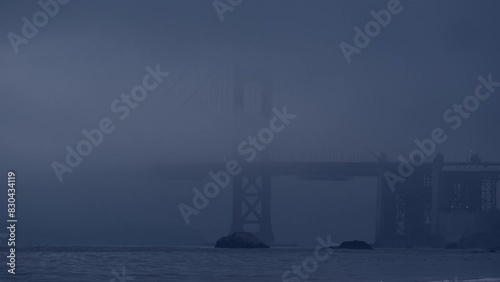 Golden Gate Bridge shrouded in fog with waves gently crashing in San Francisco Bay, viewed from Baker Beach. Perfect for relaxation and meditation. photo