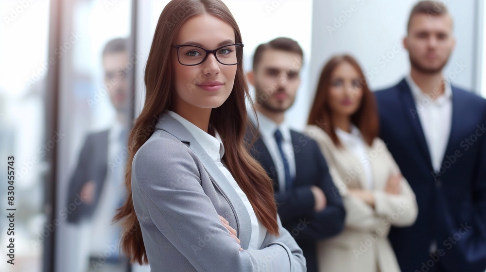 A young businesswoman wearing glasses stands in front of her team, with confident smiles on their faces and the office background. generative AI A young businesswoman wearing glasses stands in front of her team, with confident smiles on their faces and the office background. generative AI