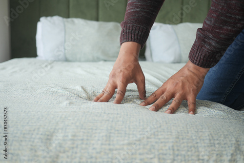  man hand touching and pressing orthopedic mattress on bed.