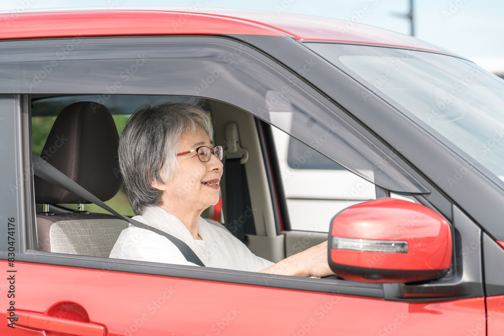 自動車の運転をする笑顔の高齢者ドライバーの女性
