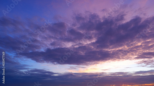 A dramatic sunset sky with a vibrant mix of deep purple and pink clouds. The lower part of the sky is illuminated with a soft orange and pink glow from the setting sun. Sunset sky background.  © Punyawee
