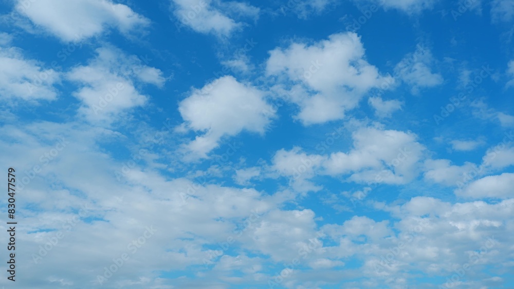 A vibrant blue sky dotted with fluffy white clouds, creating a picturesque and serene atmosphere. The clouds are scattered evenly across the sky, giving a sense of depth and dimension.
