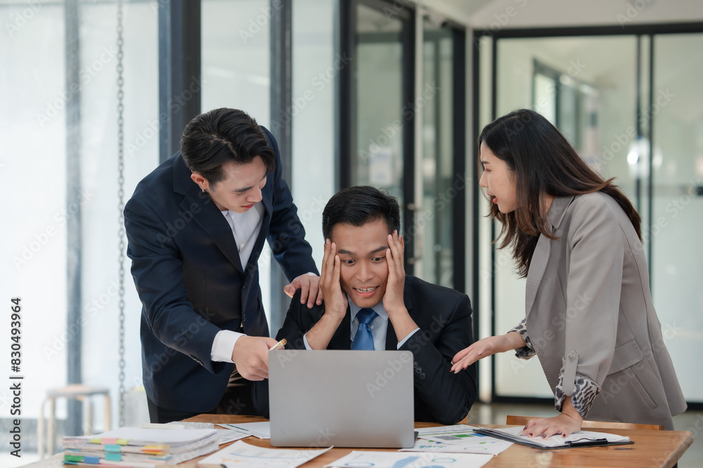 Team of stressed business professionals in office discussing problem on laptop. Overwhelmed worker receiving support and advice from colleagues. Team of stressed business professionals in office discussing problem on laptop. Overwhelmed worker receiving support and advice from colleagues.