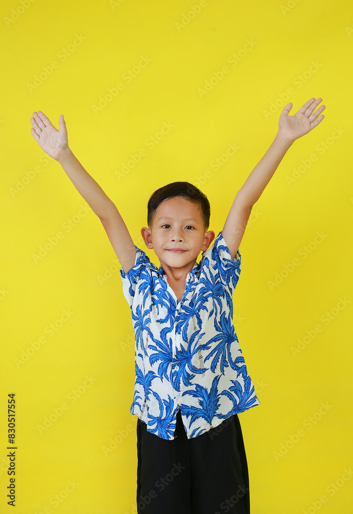 Portrait of smiling Asian boy kid in summer dress costumes raised arms or open hands wide gesture isolated on yellow background. Portrait of smiling Asian boy kid in summer dress costumes raised arms or open hands wide gesture isolated on yellow background.