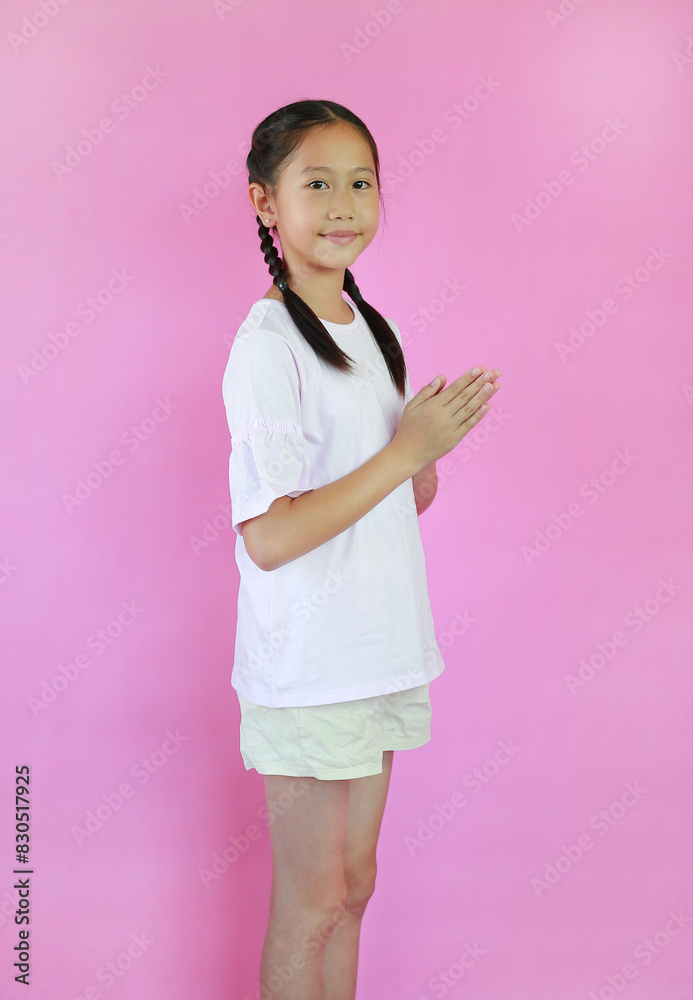 Pretty Asian young girl ages 9 years old Pay respect or pray posture isolated on pink studio background. Side view. Pretty Asian young girl ages 9 years old Pay respect or pray posture isolated on pink studio background. Side view.