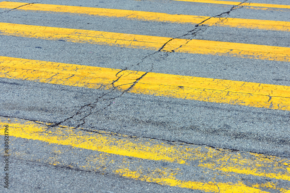 Fototapeta premium Close-up view of weathered yellow pedestrian crossing lines on an asphalt road