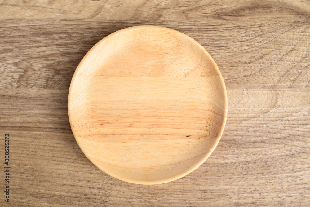 A wooden plate on wooden background, Kitchen utensil, Table top view A wooden plate on wooden background, Kitchen utensil, Table top view