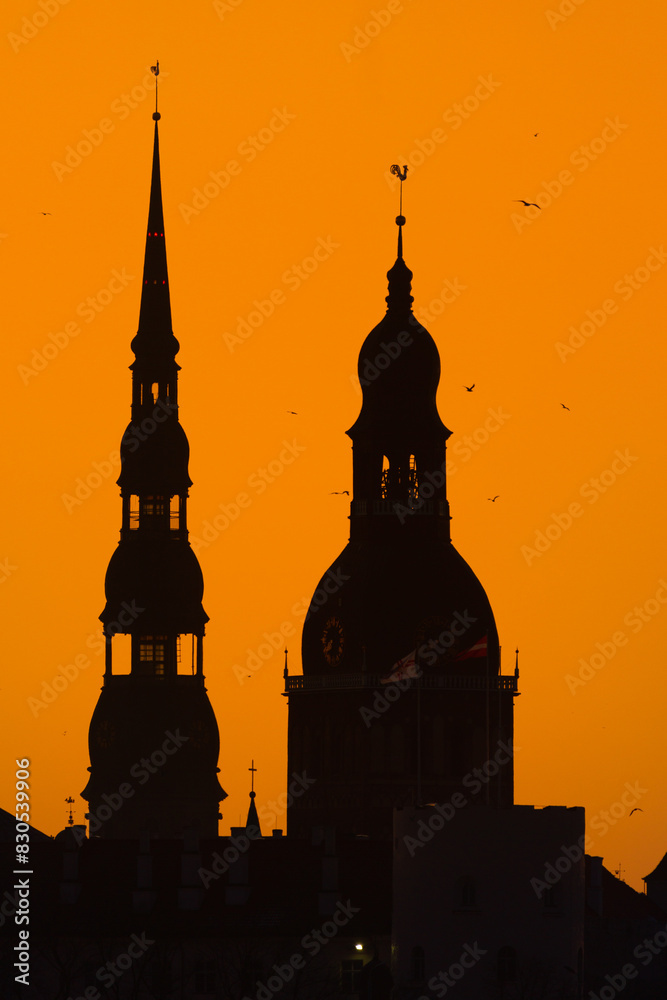 A beautiful cityscape of Riga, Latvia during sunrise. Church towers against colorful sky. City panorama in morning with buildings.