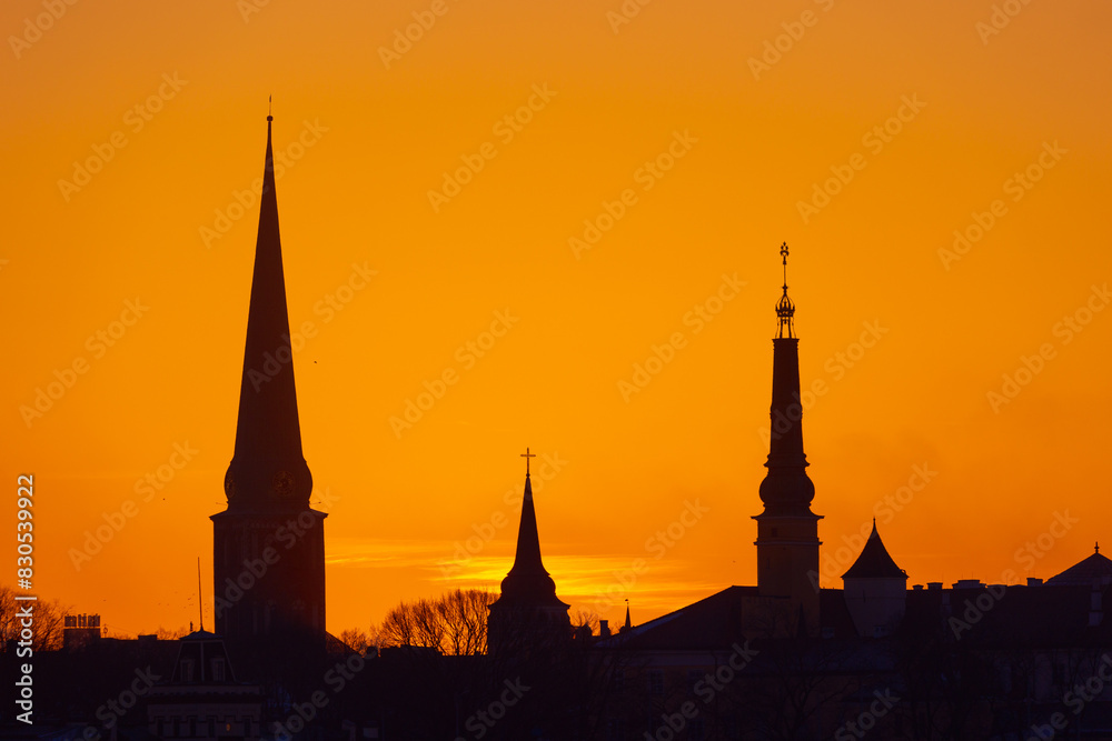 A beautiful cityscape of Riga, Latvia during sunrise. Church towers against colorful sky. City panorama in morning with buildings.