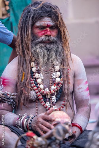 Portrait of an naga aghori sadhu holy man with pyre ash on his face and body performing aghor sadhna and smoking at harishchandra ghat in varanasi.	
 photo