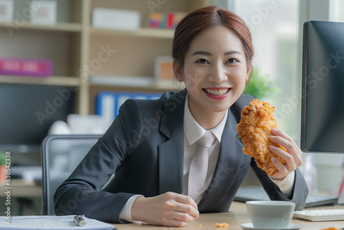 An Asian office lady holds a piece of crispy fried chicken, and her eyes sparkle with delight as she looks at it photo