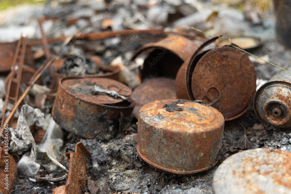 Old, rusted metal cans in burned ash. Trash in abandoned army base, burned, rusty. Old, rusted metal cans in burned ash. Trash in abandoned army base, burned, rusty.