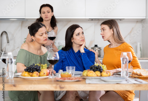 Group of women friends calming friend at house party in kitchen