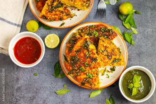 selective focus of Gujrati dish handvo slice tringle cut decorated with lemon, curry leaves, mint chutney and tomato sauce.