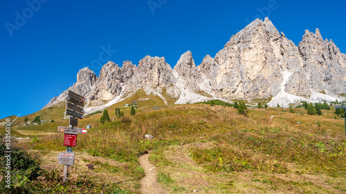 Magical Dolomite peaks of Pizes da Cir, Passo Gardena at blue sky and sunny day with a post sign trailhead showing a walking man, South Tyrol, Italy. photo