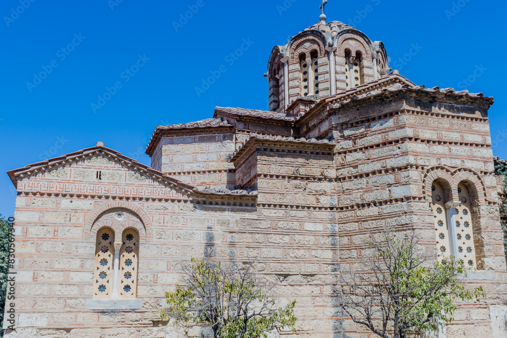 An ancient church with Byzantine architecture featuring stone walls, small windows and domes under a blue sky, in Athens, Greece