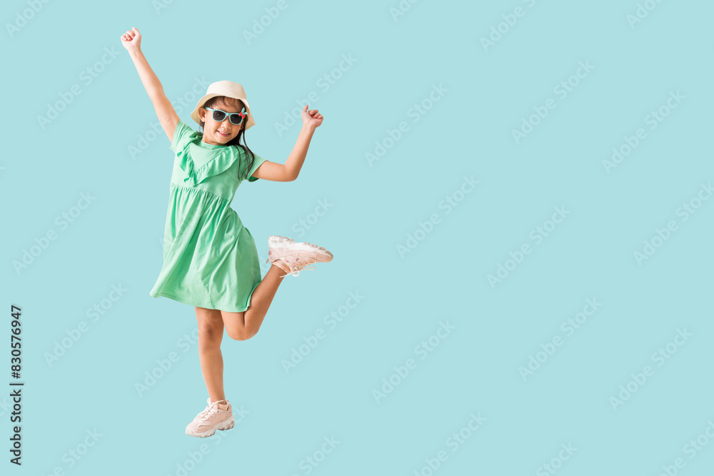 Happy smiling asian little girl and jumping, dancing were hat and sunglasses posing, Fashion summer holiday concept, Full body isolated on blue background