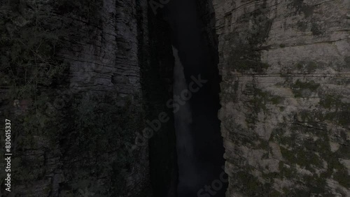 Drone flies backwards out of dark canyon with Fumacinha waterfall photo