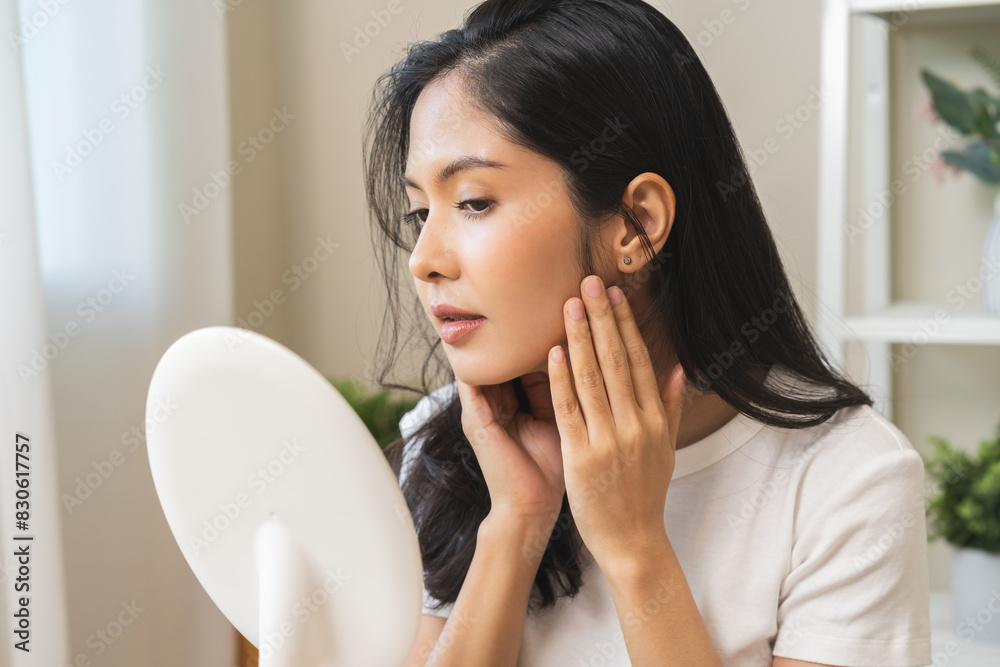 Anti aging beauty, happy asian young woman looking in mirror reflection at home, touching face skin satisfied with healthy moisturized, skin care treatment cosmetic for dry skin during morning routine Anti aging beauty, happy asian young woman looking in mirror reflection at home, touching face skin satisfied with healthy moisturized, skin care treatment cosmetic for dry skin during morning routine