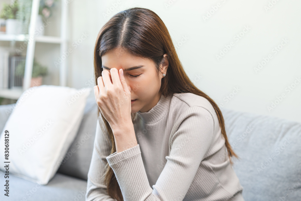 Depressed anxiety asian young woman, girl frustrated closed eyes, touching face suffering stressed, sick, tired, crisis sitting on sofa from headache, migraine pain tension problem health care concept Depressed anxiety asian young woman, girl frustrated closed eyes, touching face suffering stressed, sick, tired, crisis sitting on sofa from headache, migraine pain tension problem health care concept