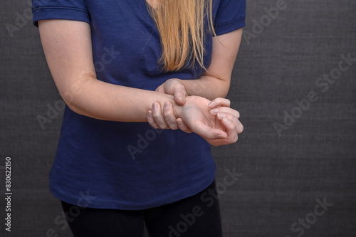 Ból i drętwienie ręki, kobieta trzyma się za swój nadgarstek