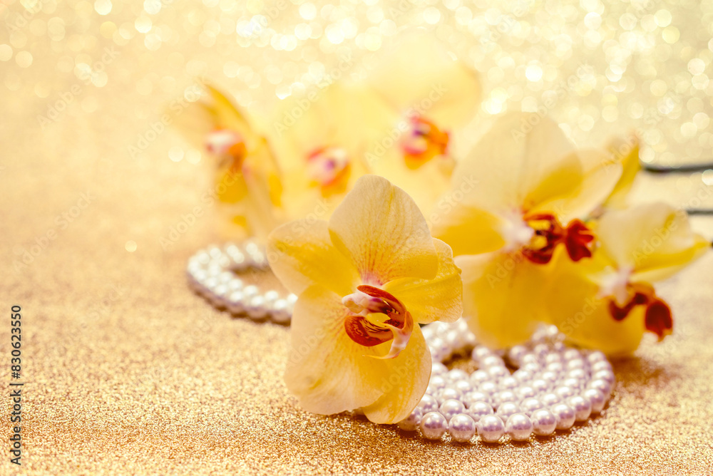 yellow Orchid and pearl necklace on a shiny gold background yellow Orchid and pearl necklace on a shiny gold background
