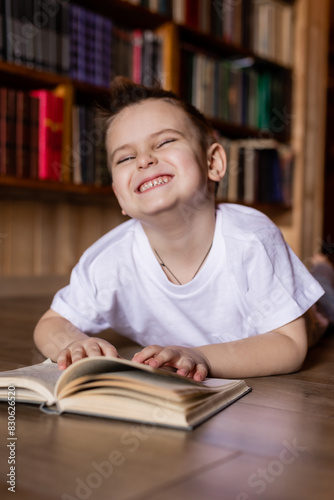 little boy is reading a book in the library at home