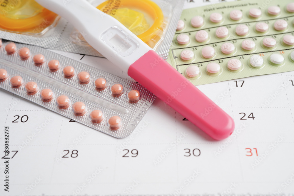 Pregnancy test with birth control pills and condom for female on calendar, ovulation day. Pregnancy test with birth control pills and condom for female on calendar, ovulation day.
