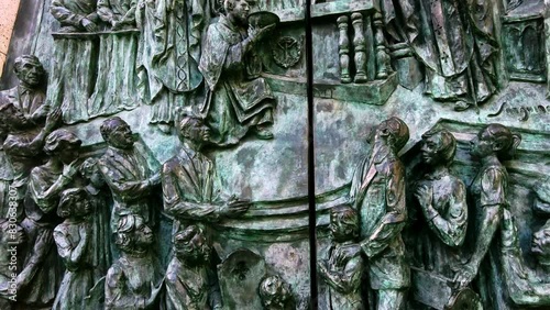 close up details of religious gathering depicted on bronze church door of Catedral De La Almudena in Madrid photo