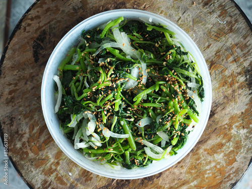 top view bowl of spinach with white sesame seed and onion salad