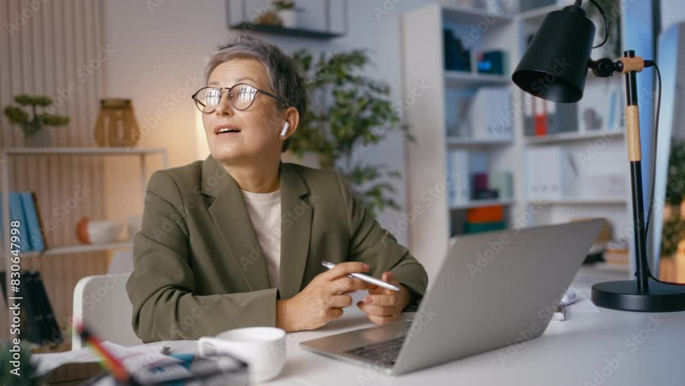 Grey-haired businesswoman communicates with partners on phone in her office Grey-haired businesswoman communicates with partners on phone in her office