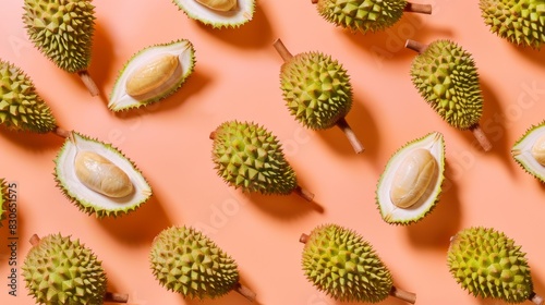 Durian fruit slices and whole, flat lay on a bright peach background.
