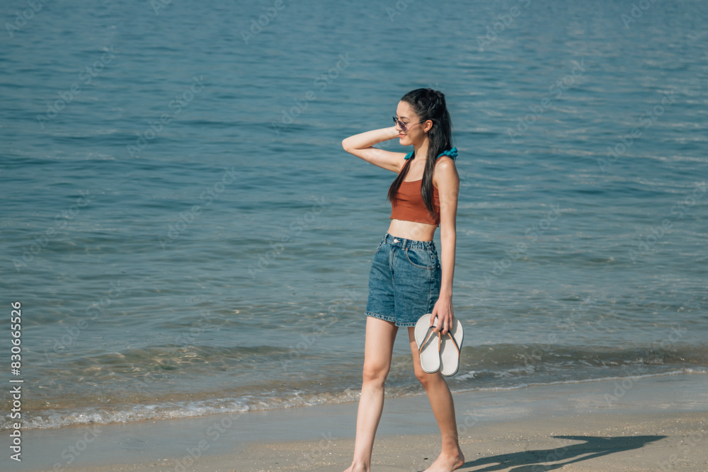 young tourist woman walking along the beach shore young tourist woman walking along the beach shore