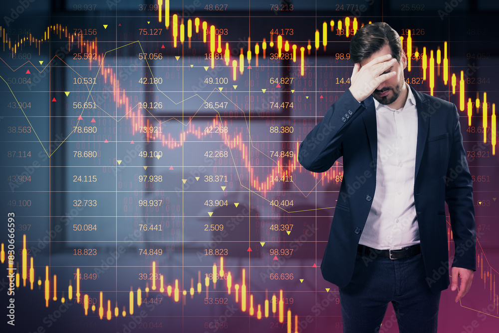 Stressed young european businessman with downward red forex candlestick hologram on blurry office interior background. Financial crisis, stock and recession concept. Double exposure. Stressed young european businessman with downward red forex candlestick hologram on blurry office interior background. Financial crisis, stock and recession concept. Double exposure.