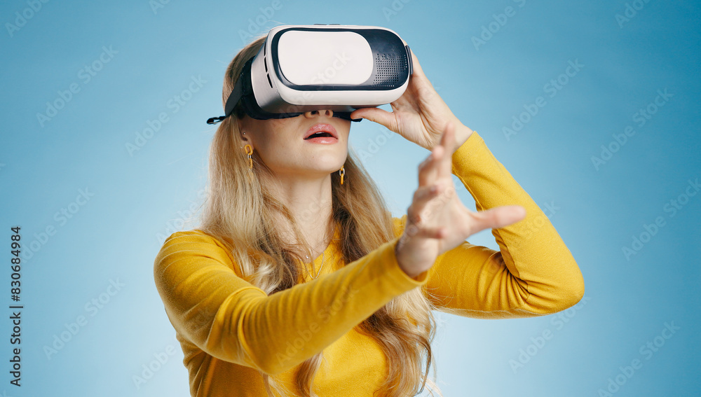 VR, woman and hand in studio for metaverse, digital and video game on blue background. Technology, virtual and streaming for gamer person, hobby and internet for 3d augmented reality experience VR, woman and hand in studio for metaverse, digital and video game on blue background. Technology, virtual and streaming for gamer person, hobby and internet for 3d augmented reality experience