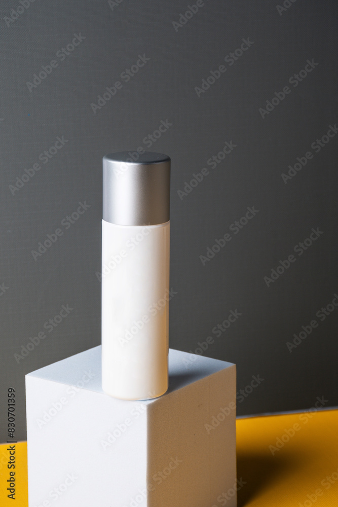 Plastic white tube for cream or lotion. Skin care or sunscreen cosmetic on grey and yellow background. Plastic white tube for cream or lotion. Skin care or sunscreen cosmetic on grey and yellow background.