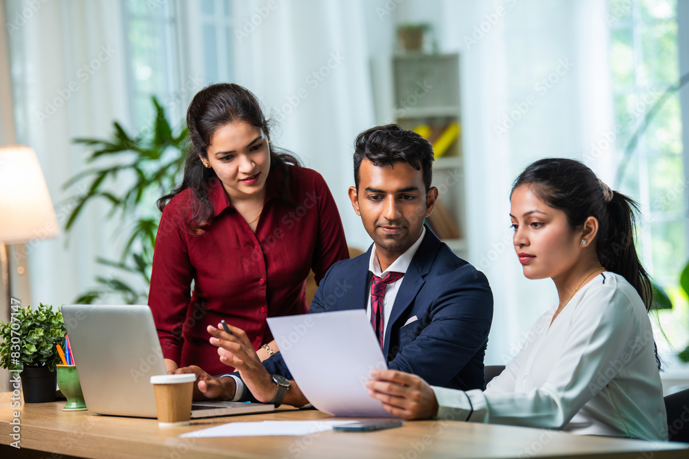 Indian young businesspeople using laptop in group meeting at desk Indian young businesspeople using laptop in group meeting at desk