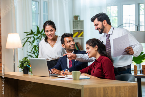 Indian young businesspeople using laptop in group meeting at desk