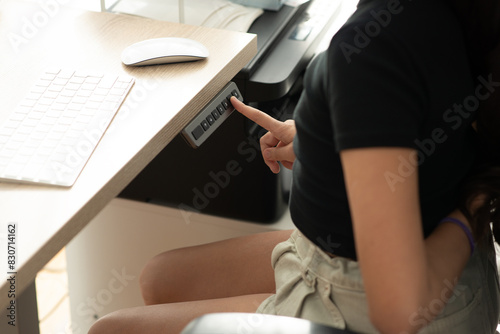 Young girl or woman using an Ergonomic electric desk or Adjustable height table, for a better position in order to avoid back pain at the office