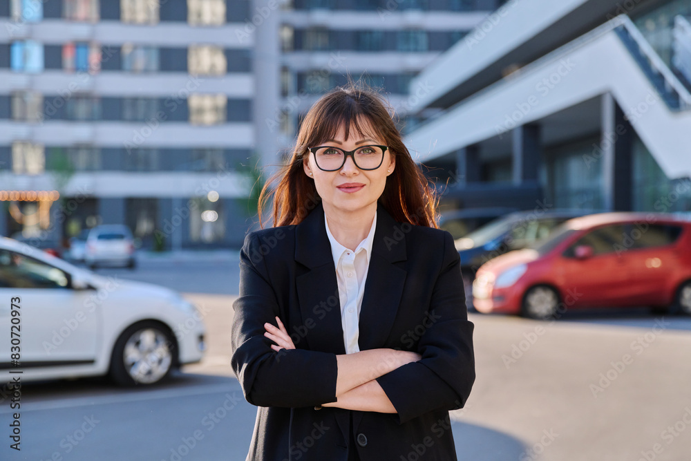 Mature confident business woman with crossed arms in black suit outdoors Mature confident business woman with crossed arms in black suit outdoors