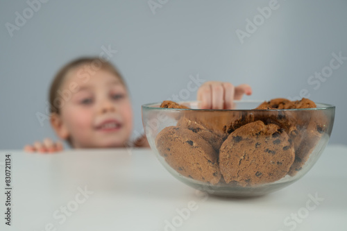 Little girl steals cookies from the table. 