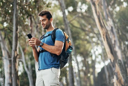 Man, hiking and smile with smartphone in forest for browsing internet, networking and social media. Fitness, survival and workout in woods on countryside with texting, message and chat on app