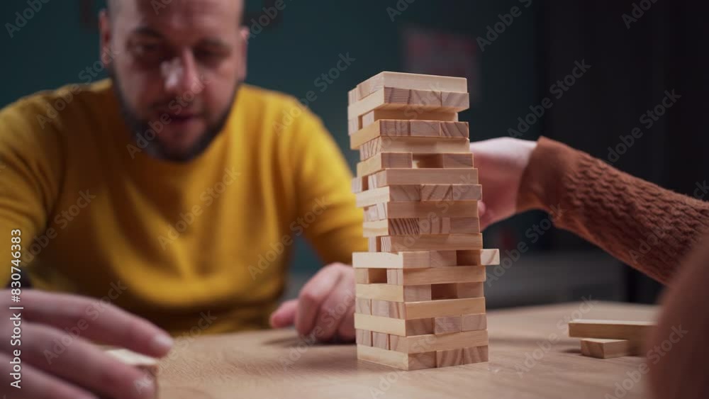 Players stack wooden blocks in a challenging game of precision and strategy on a tabletop