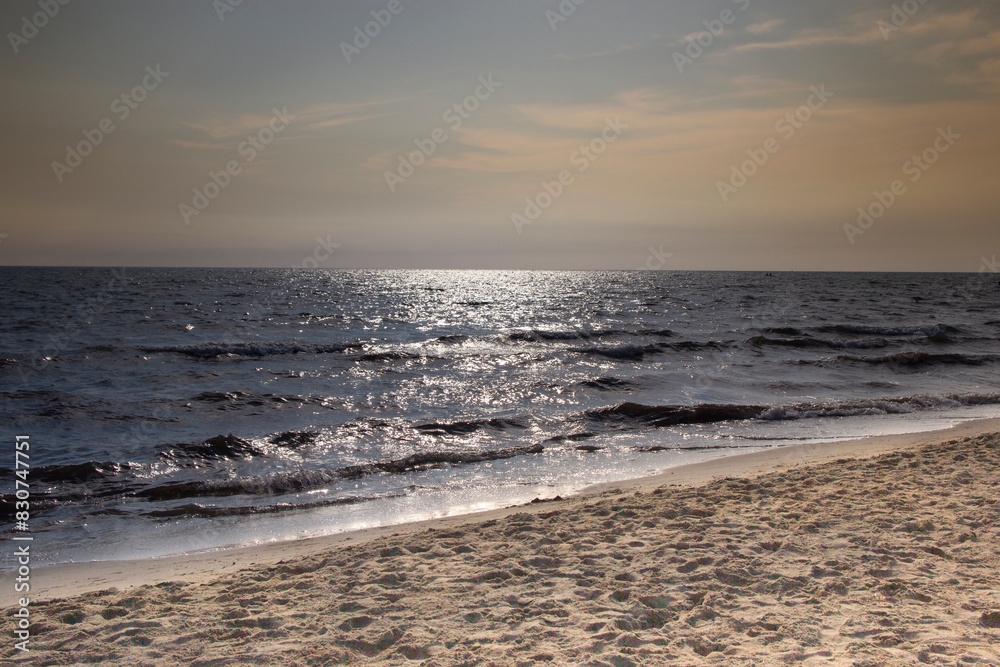 dark blue sea with silver sun reflections on the water, beautiful sun reflections on the sea, dark blue sea and sandy beach