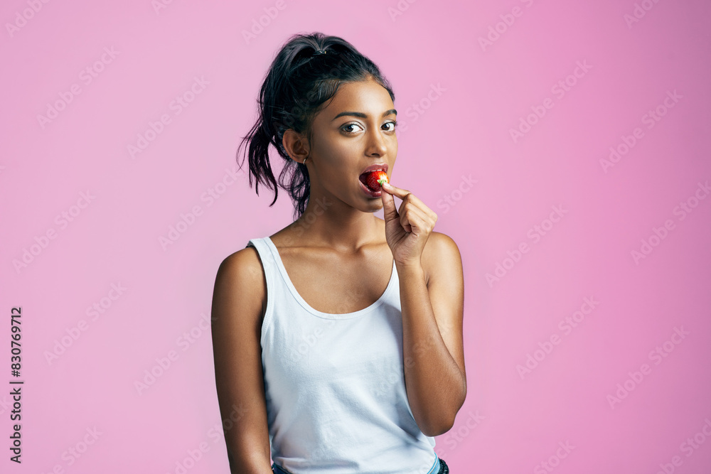 Fruit, portrait and girl with strawberry in studio for diet, healthy snack or wellness on pink background. Food, eating and hand of Indian woman for detox, antioxidants or weight loss on mockup Fruit, portrait and girl with strawberry in studio for diet, healthy snack or wellness on pink background. Food, eating and hand of Indian woman for detox, antioxidants or weight loss on mockup