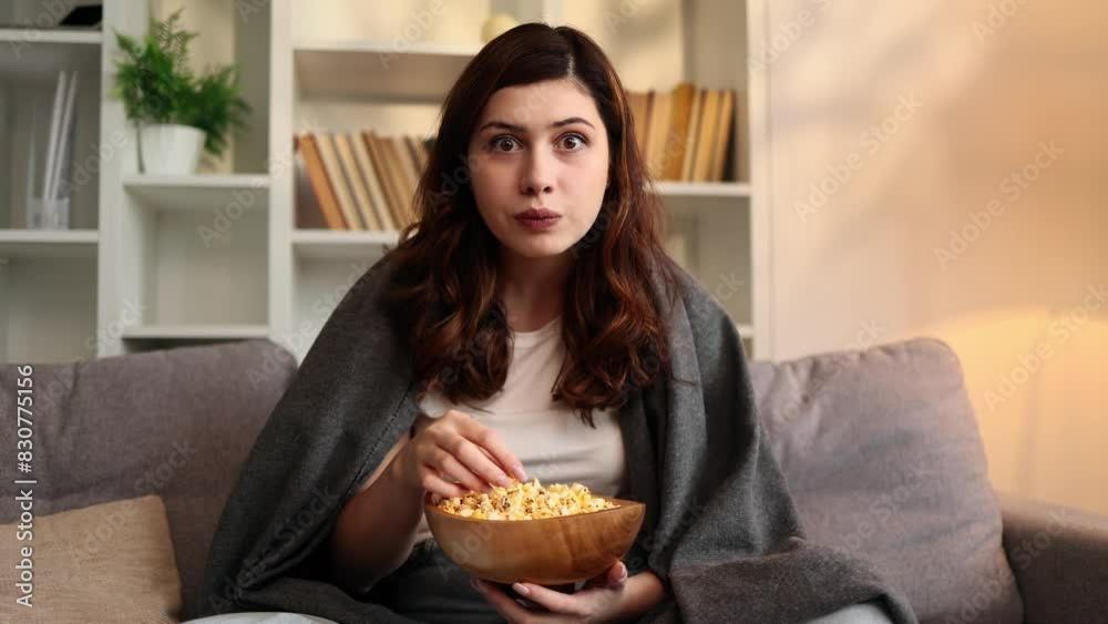 Close up portrait of addicted focused young woman looking at camera while watching interesting TV program film movie and eating popcorn at home Enchanted brunette girl cannot take her eyes off indoors Close up portrait of addicted focused young woman looking at camera while watching interesting TV program film movie and eating popcorn at home Enchanted brunette girl cannot take her eyes off indoors