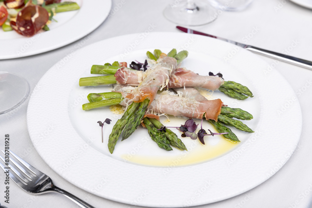 Top view of a rolled asparagus served with cheese on a white plate Top view of a rolled asparagus served with cheese on a white plate