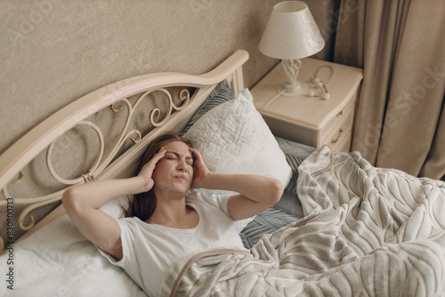 Young woman with headache flu ill sick disease cold at home indoor lying on bed
